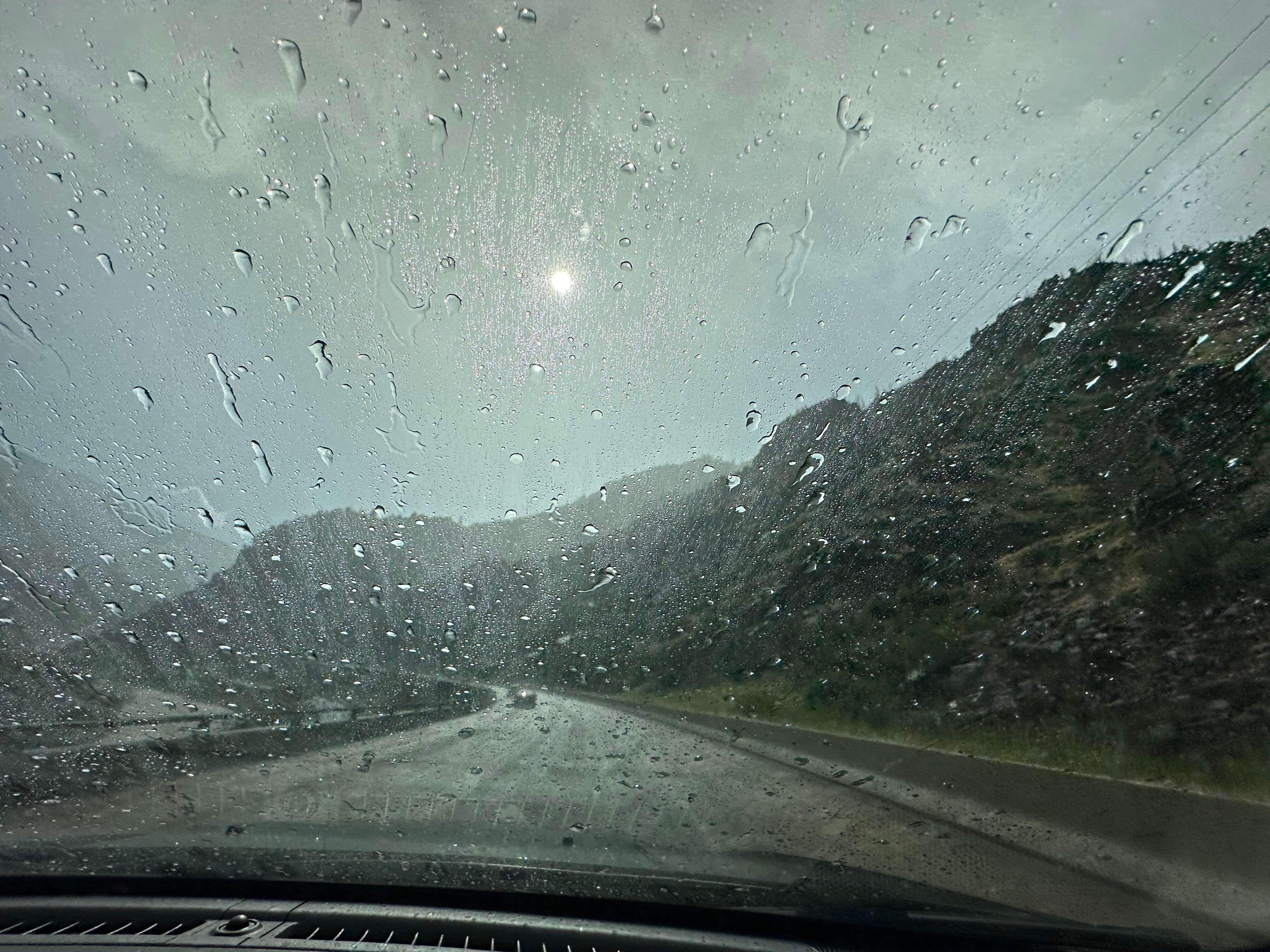 Windshield with rain driving on a road in a canyon